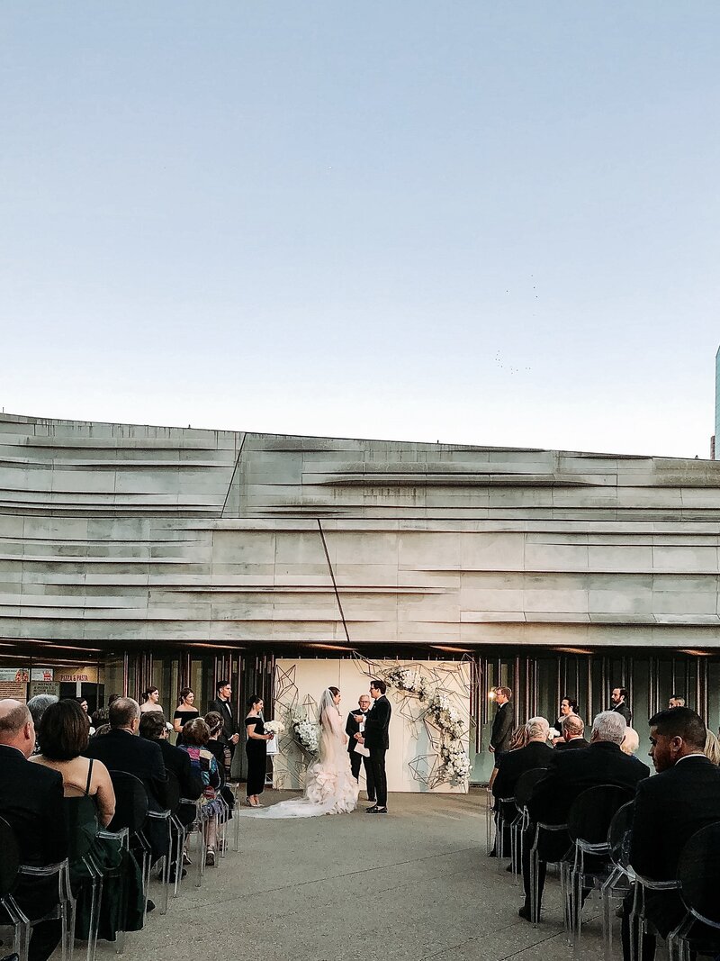 A Texas wedding ceremony in front of a modern building captured by a talented wedding videographer.
