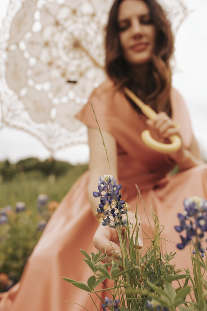 close up of a woman in a pink dress picking a lavender flower