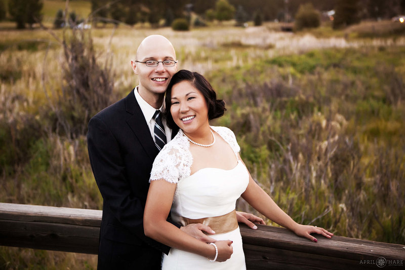 Bride and groom pose for a portrait at their August wedding on the wood boardwalk at Evergreen Lake House