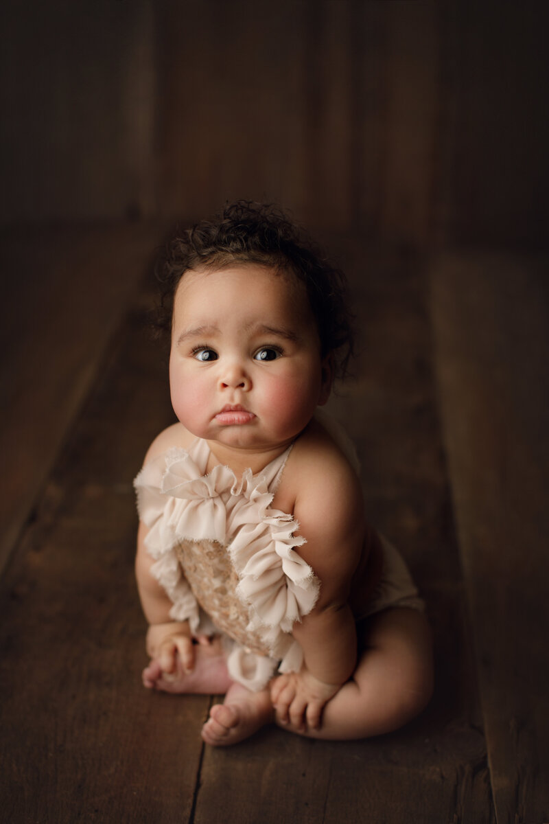 baby girl in sparkly outfit on wooden backdrop