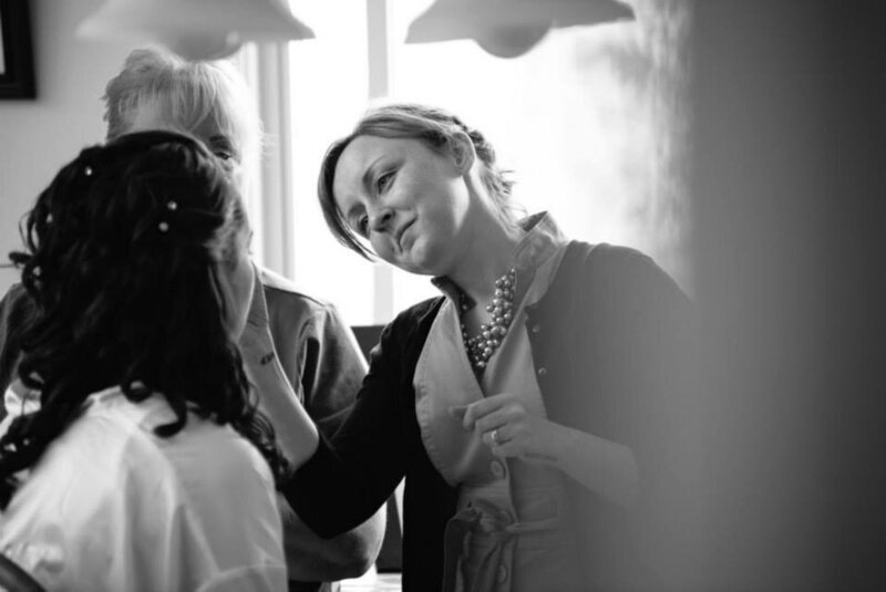 Holly, Michigan based makeup artist Danielle Neiswender applies makeup to her bride while the mother of the bride looks on.