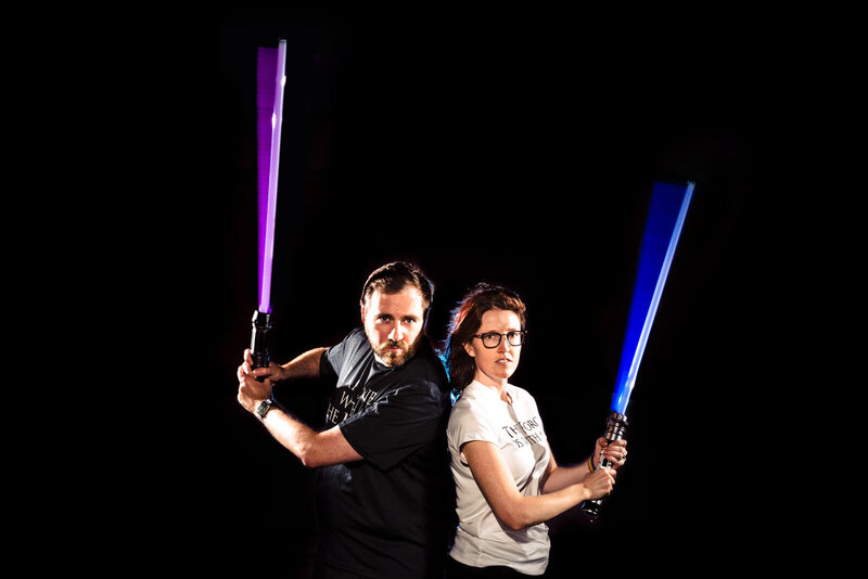 Elyssa and John Kivus, Raleigh wedding photographer team, stand back to back while brandishing light sabers