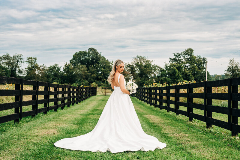 Bride in white dress along black fence Outdoor venue