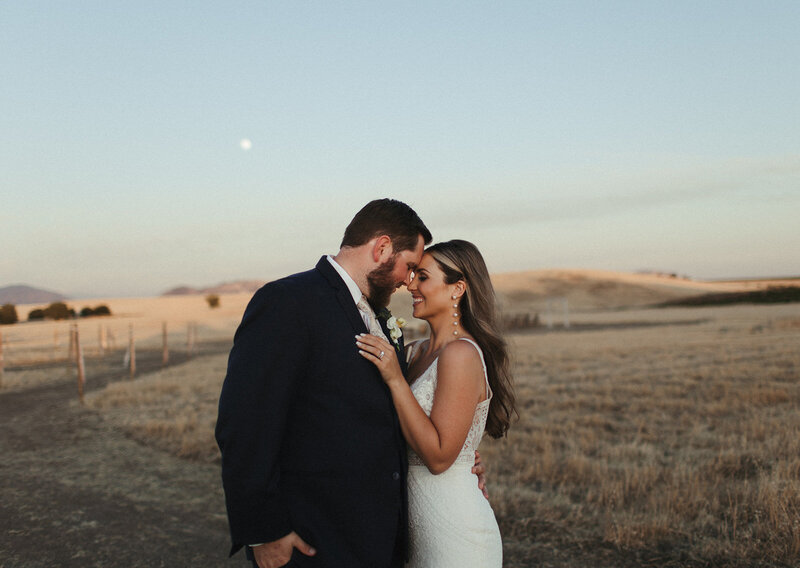 Bride and Groom stand together on wedding day with bridal bouquet