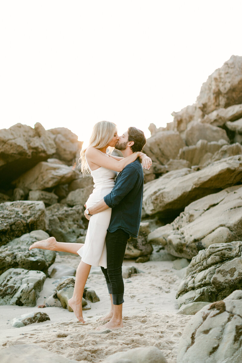 Engaged couple kiss on the beach during engagement photography session