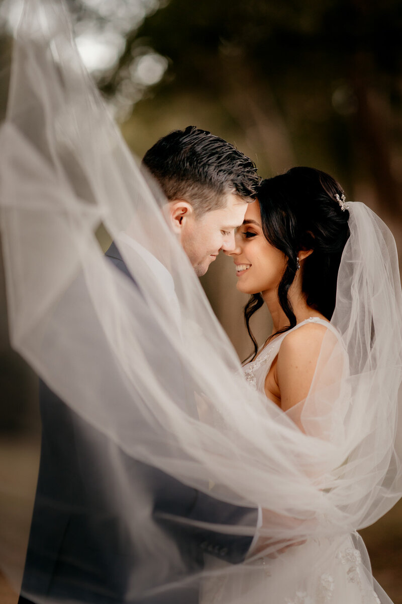 Newly-weds hold each other as they're covered with flying veil
