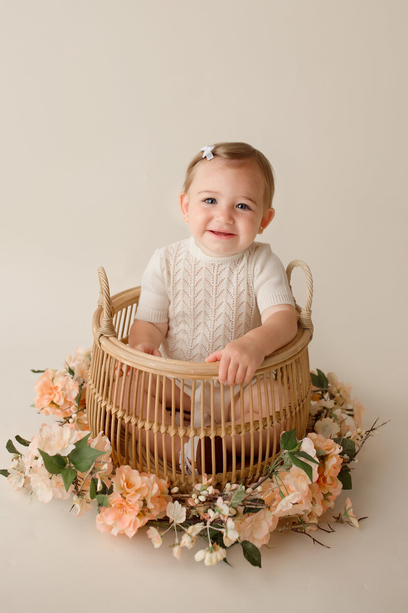 sweet girl sitting in a bamboo basket during her birthday session