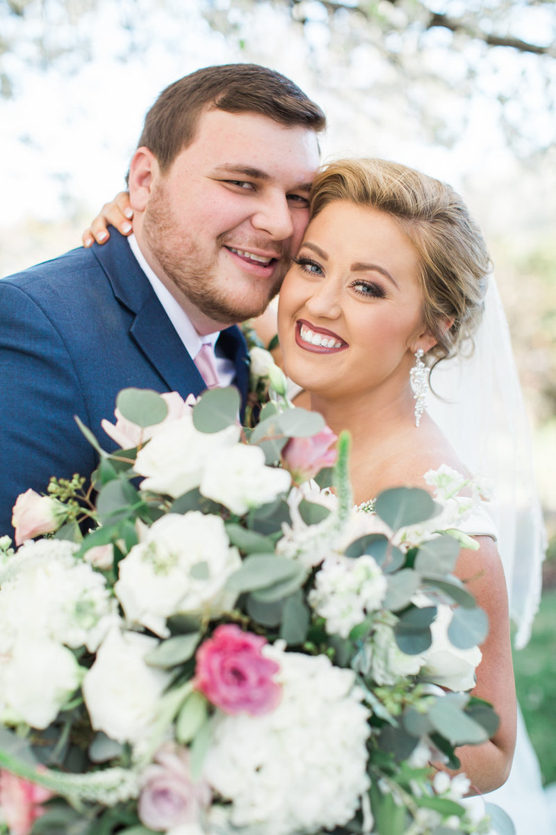 Wedding Photography, bride and groom looking into the camera with large bouquet