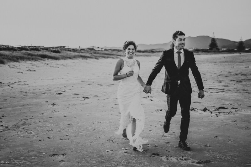 Wedding couple running on the beach holding hands