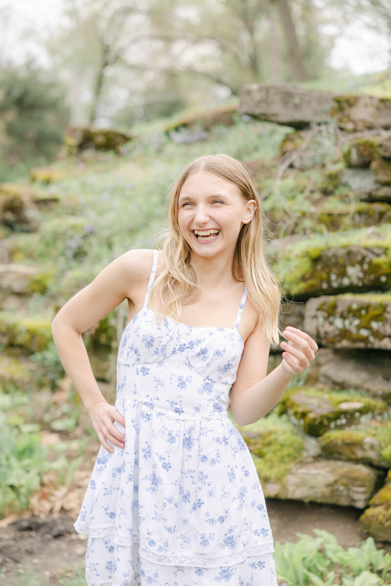 girl laughs with one hand on her hip in a blue floral dress, Indianapolis senior photographer