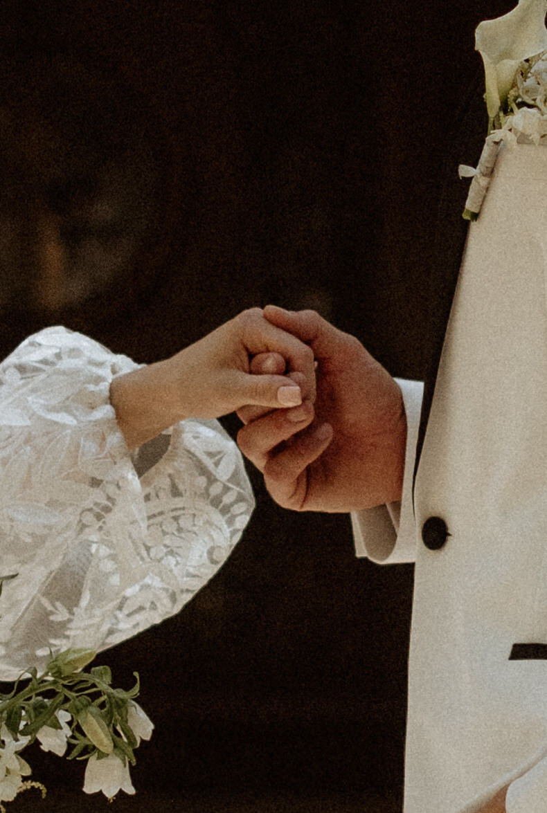 Close up of bride and groom holding hands