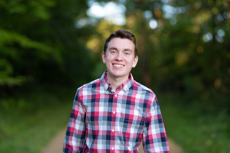 High school senior boy smiles in checked shirt for his senior portrait