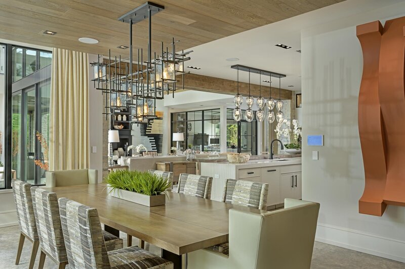Modern Dinning Room with open Kitchen featuring over island pendants and exposed wood pillar. Glass enclosed office space. Open living room. Orange Modern art sculpture.