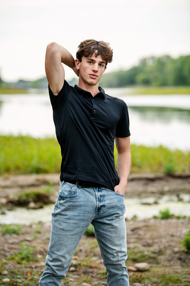senior photo of guy wearing black tshirt and jeans in nature