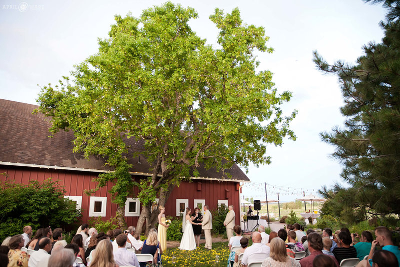 Wedding ceremony next to red barn at Chatfield Farms