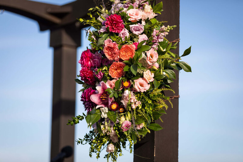Pink and purple flowers on a wedding arbor.