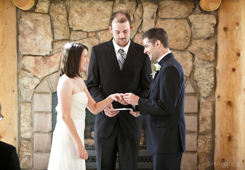Bride and groom get married in front of stone fireplace inside the Meadow Creek Lodge & Event Center Pavilion in Colorado
