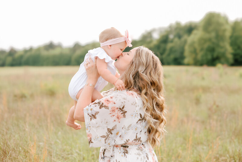 Mom kissing her toddler on the lips while holding her up during a Raleigh NC maternity photo session. Photographed by Raleigh maternity photographers A.J. Dunlap Photography.