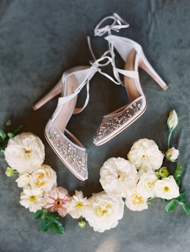 White luxury wedding shoes with intricate jewels on the toes by Belle belle surrounded by white and blush garden roses photographed by My Sun and Stars Co
