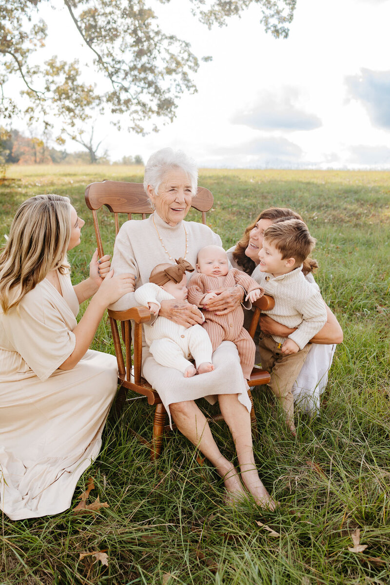 grandma holding twin babies and surrounded by family