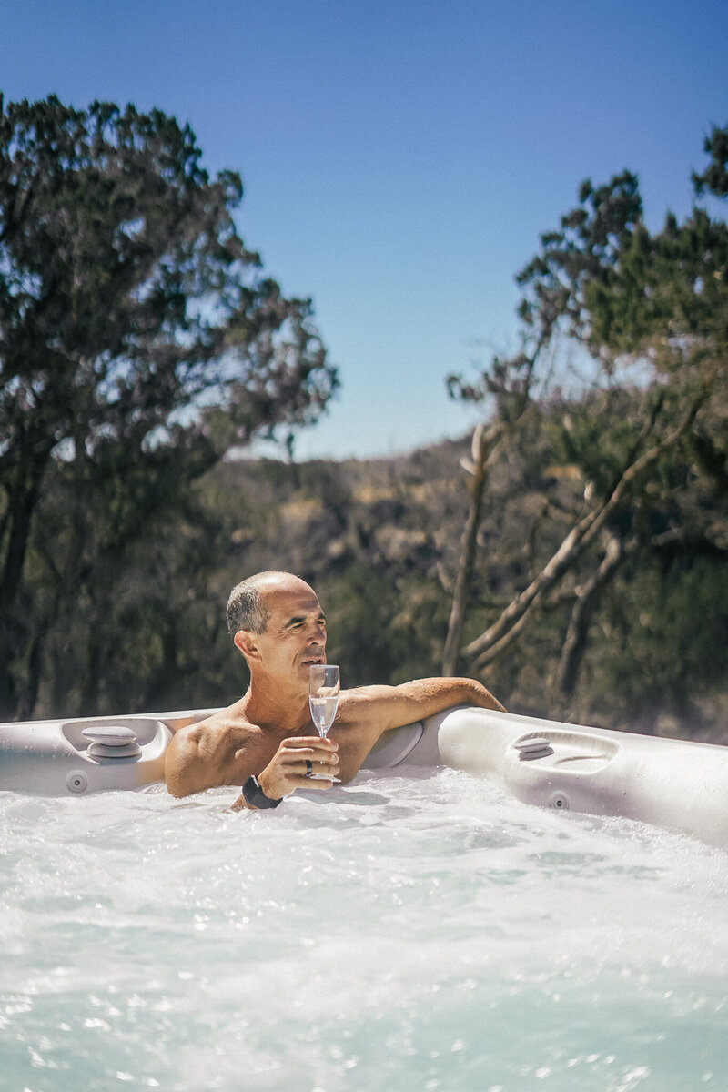 Man sitting in a hot tub with a wine glass