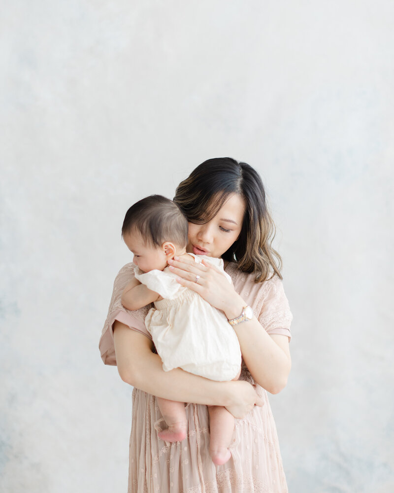 Mother embraces her baby during portrait session