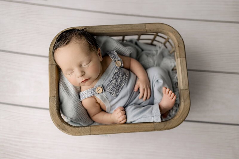 Baby boys dressed in blue overalls Place gently in a crate on a wood floor