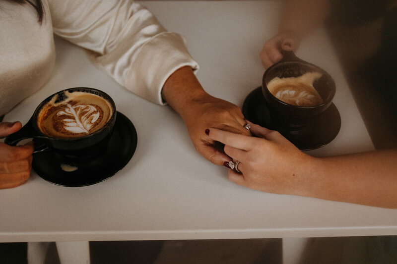 couple holding hands and drinking coffee together