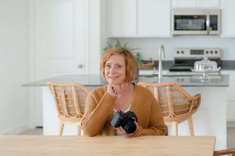 Image of Lady with camera sitting at table smiling