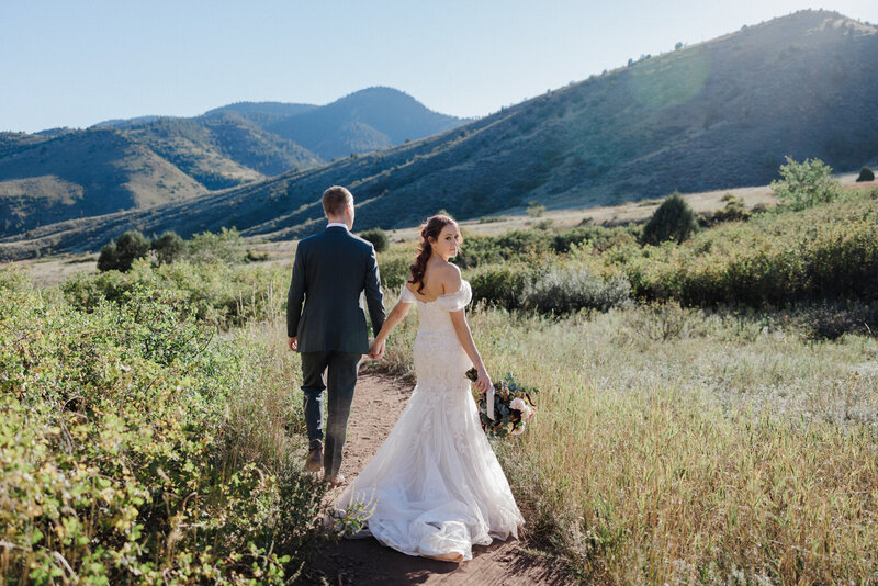 Bride and groom walk together during Red Rocks micro wedding in Denver, CO.