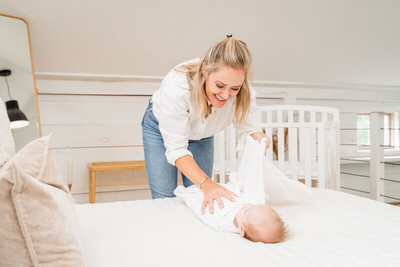 Snooze Clues founder and coach Kristen swaddling a baby
