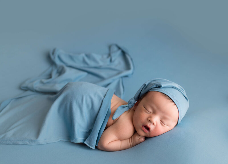Baby with sleepy hat on blue fabric
