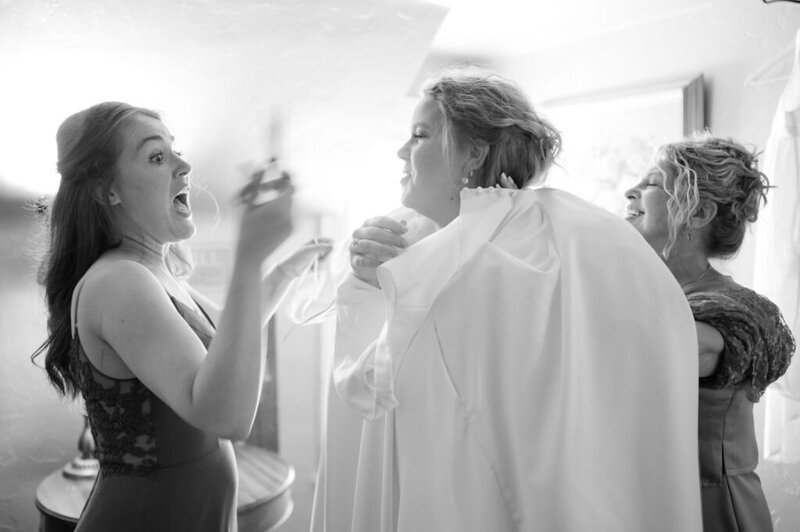Mom and sister help the bride into her dress.