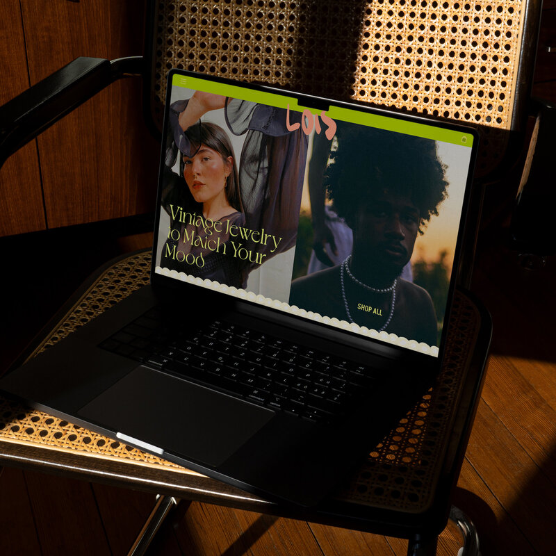 Laptop on a chair showing the bold website design of Lois vintage jewelry