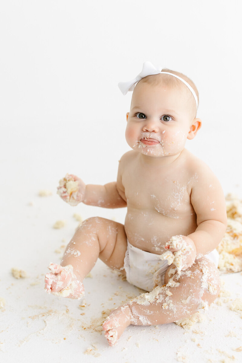 Baby girl covered in cake and icing during her cake smash session