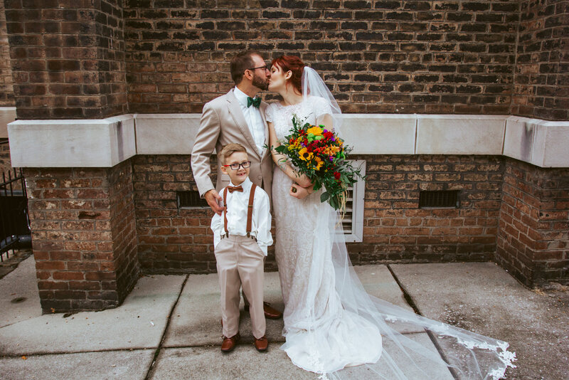 bride and groom kissing with young boy