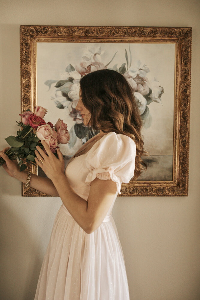 a woman in a flowy pink dress holding a bouquet of pink roses