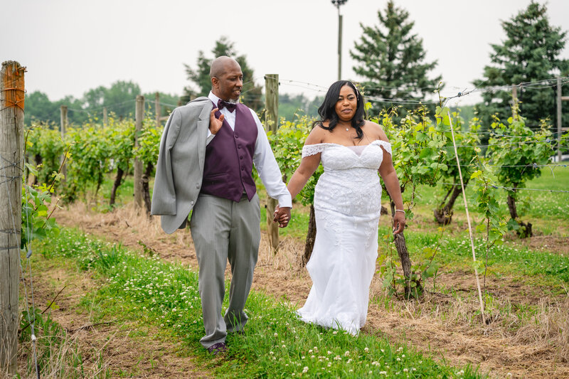 Bride and groom walking hand in hand through vineyard smiling – photographed by wedding photographer Niko Coric – Lumen Clarity Media