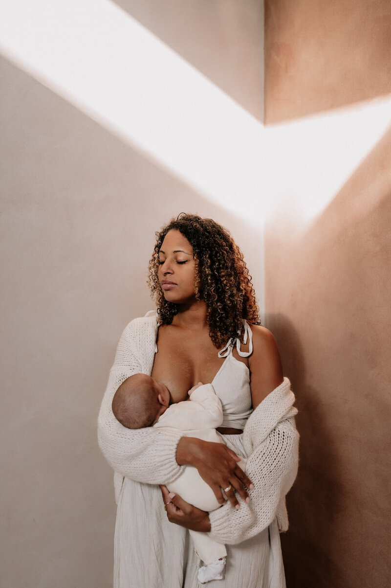 mama geeft borstvoeding aan pasgeboren baby tijdens newbornshoot