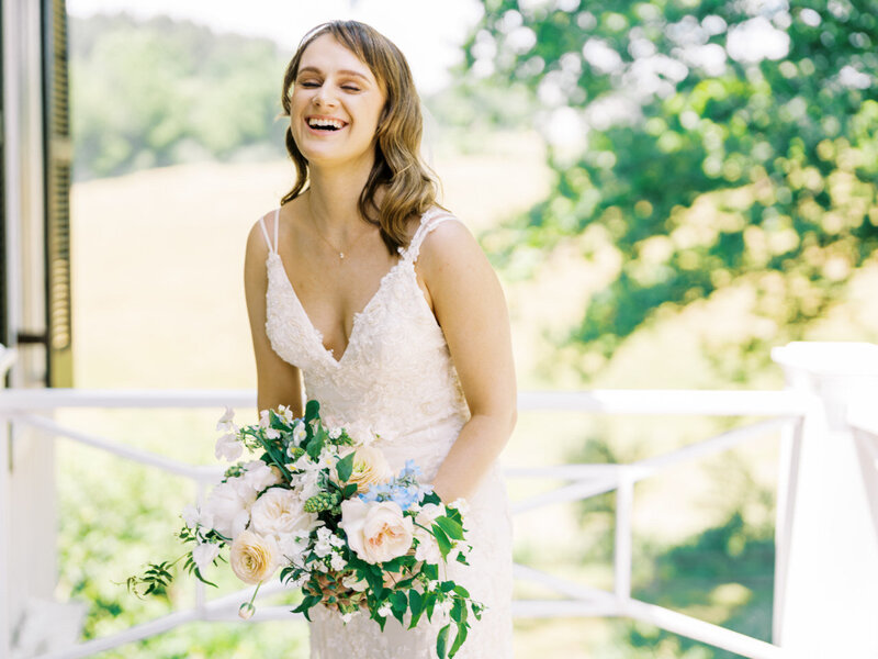 A girl with curled hair and natural makeup smiling with a bouquet of spring flowers in Charlottesville, Virginia