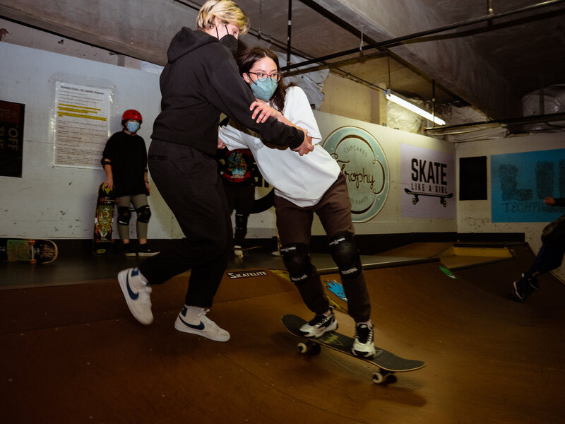 Skate teacher helping skateboarder down a ramp