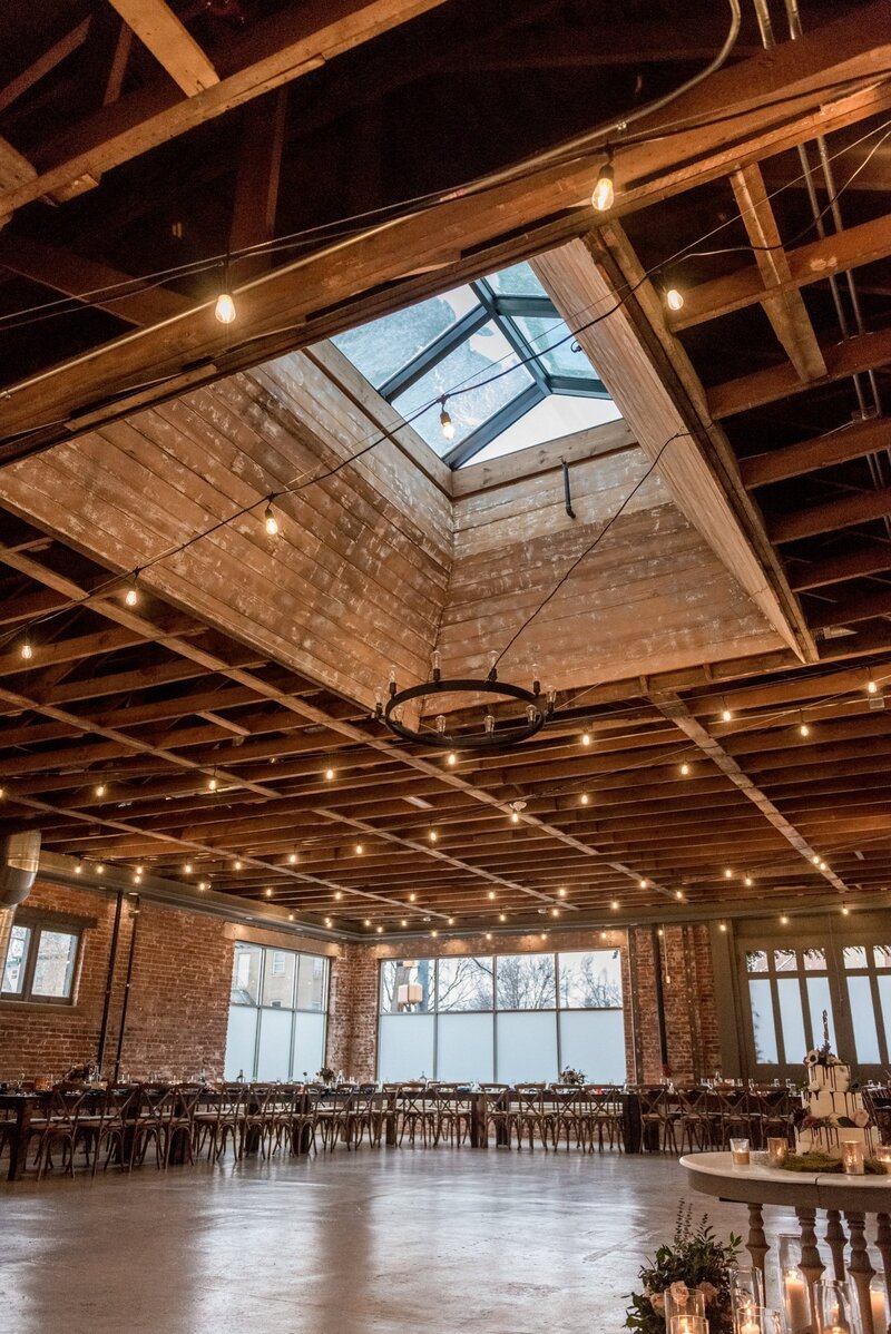 Inside the St Vrain wedding venue in Longmont Colorado with exposed beams, brick walls and fairy lights