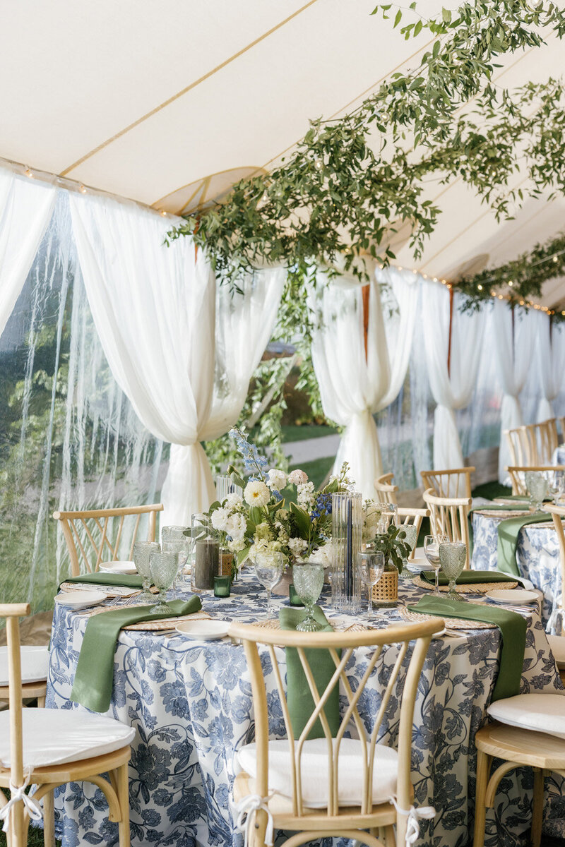 Close up of a tented wedding with pops of blue, white and green