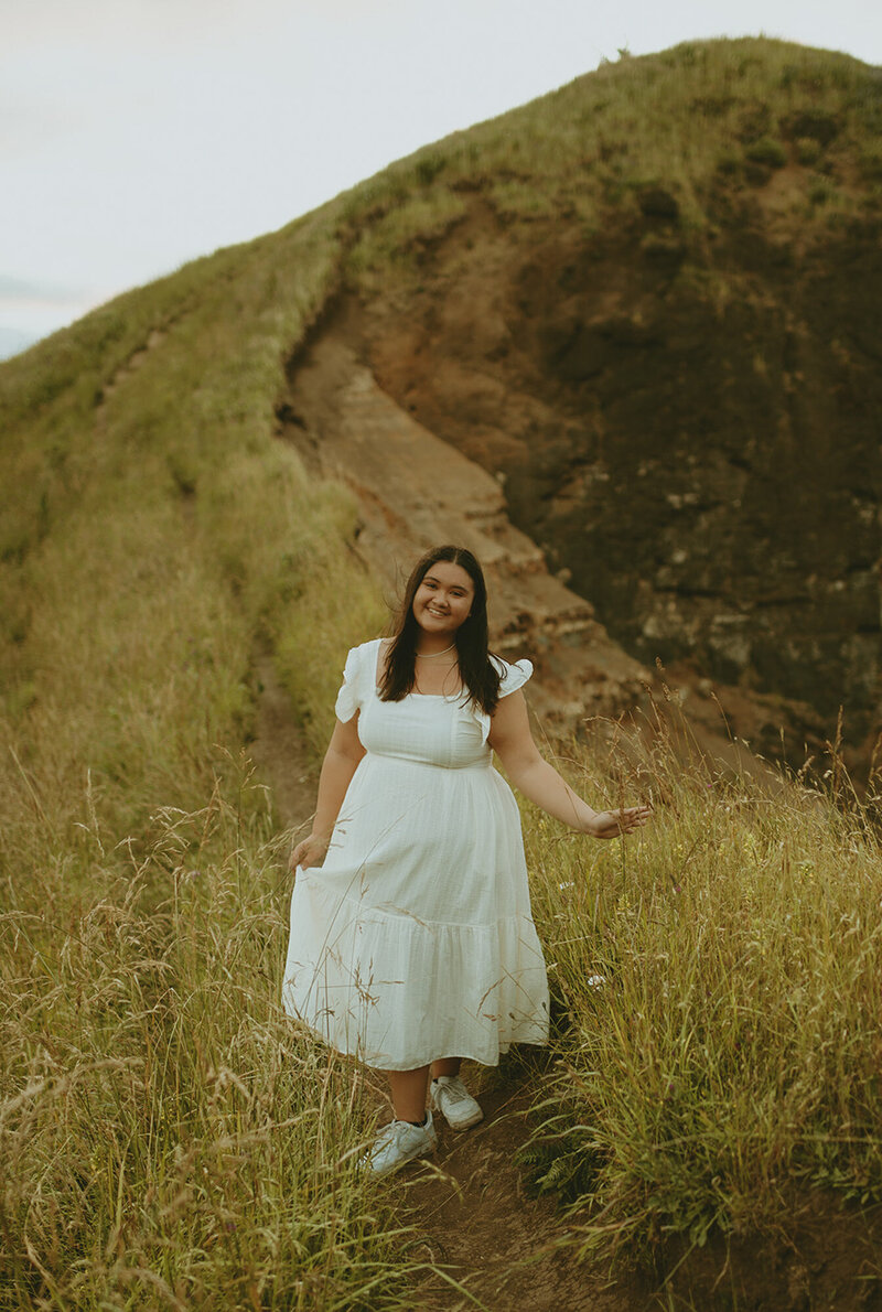 girl in white dress and sneakers standing on grassy path