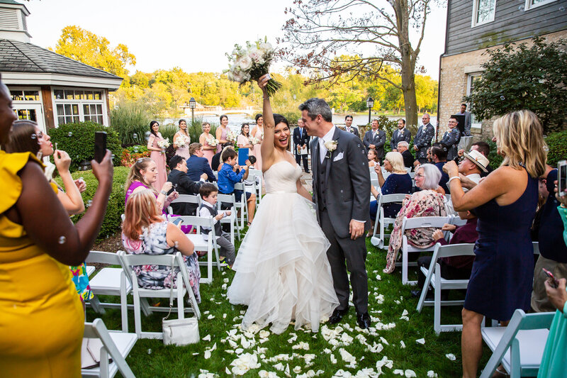 A cheerful bride and groom walking down the aisle at their intimate outdoor wedding ceremony at the Herrington Inn in Geneva, IL.