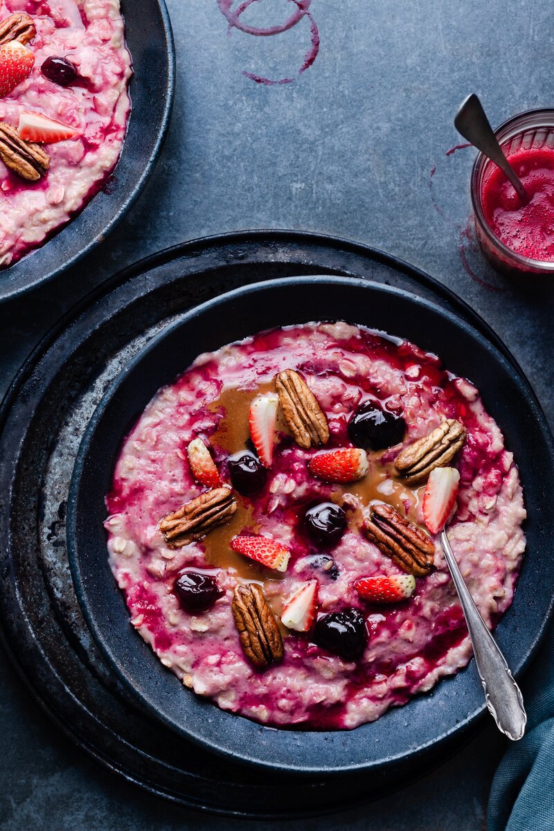 Pink oatmeal bowl with berries and nuts  on top