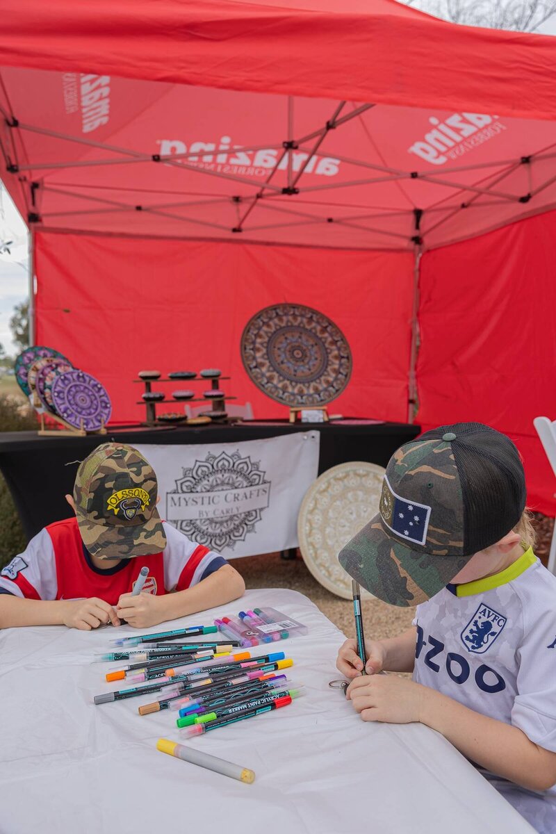 Children sitting at a craft table colouring during a community market event by events photography