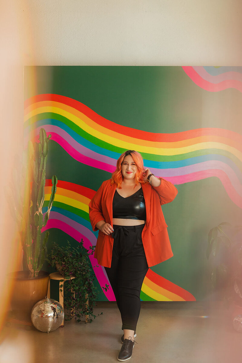 A person walking in front of a rainbow mural.