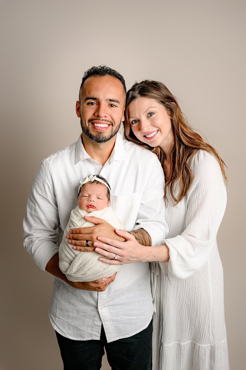 charlotte dad hods his newborn daughter while his wife leans against his shoulder 