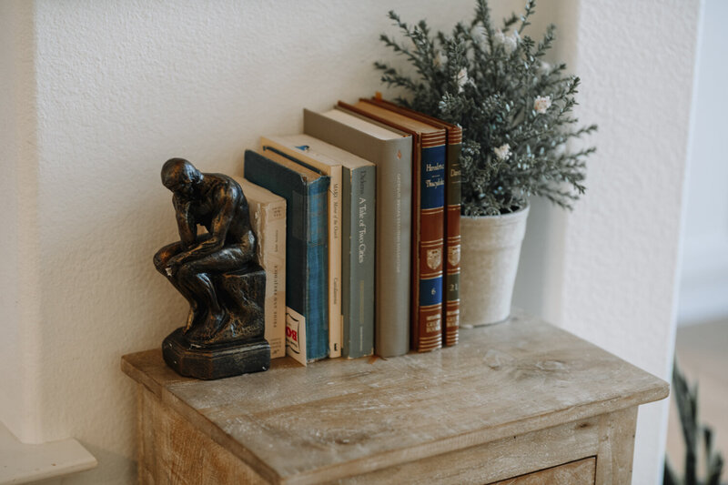 a stack of books on a shelf with a plant and book end